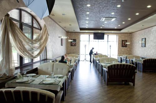 a restaurant with tables and chairs and a man standing in the distance at Hotel Zolotoy Globus in Pyatigorsk