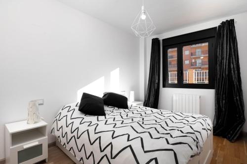 a bedroom with a black and white bed and a window at Apartamento en Sabiñánigo con amplia y soleada terraza in Sabiñánigo