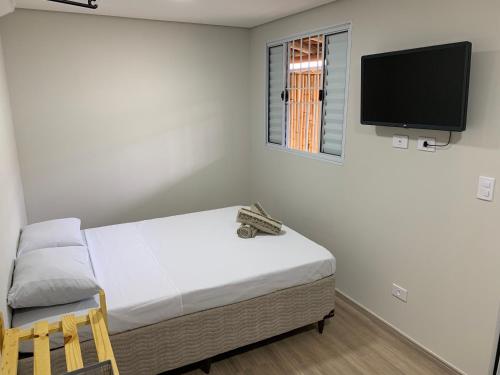 um quarto com uma cama e uma televisão de ecrã plano em Chalé Casal Perto Praia LAGOINHA - Wi-Fi e Ar-Condicionado - Vila Santa Barbara em Ubatuba