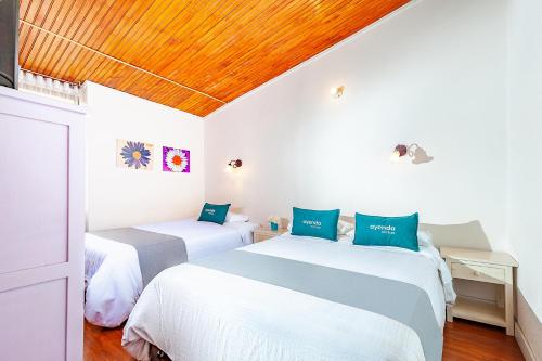 Ayenda Casa La Castellana في باستو: سريرين في غرفة نوم ذات سقف خشبي