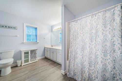 a bathroom with a toilet and a shower curtain at Gone With the Wind in Duck