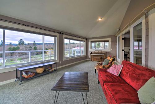 a living room with a red couch and large windows at Breathtaking Port Ludlow Home with Deck and Yard in Port Ludlow