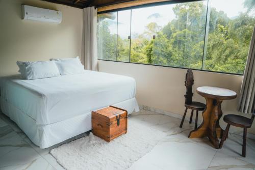 a bedroom with a bed and a table and a window at Diver Village Ilhabela in Ilhabela