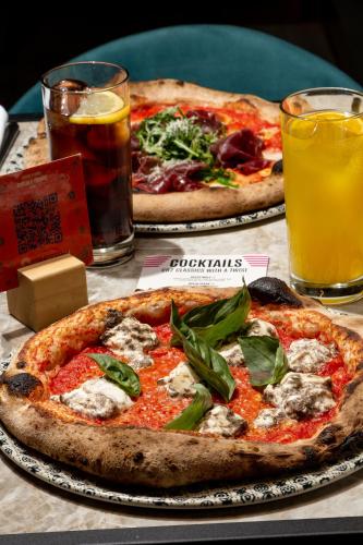 two pizzas on a table with two glasses of beer at Pestana CR7 Gran Vía Madrid in Madrid