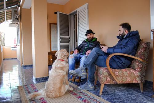 two men and a dog sitting in a living room at The Bearded Dad Hostel in Tirana