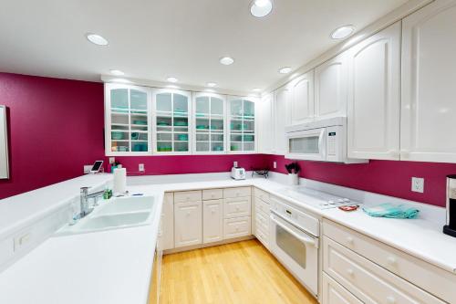 a kitchen with white cabinets and purple walls at The Avon Spot in Avon
