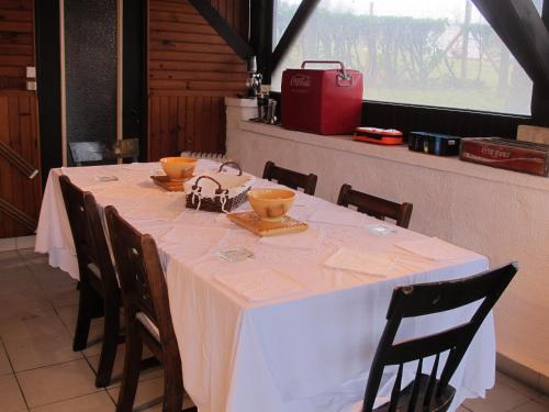 une table avec une nappe blanche et des bols dessus dans l'établissement poppy chambres d'hotes, à Tursac