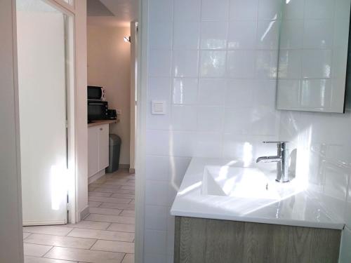 La salle de bains est pourvue d'un lavabo et d'un mur carrelé blanc. dans l'établissement Le Baionarena 4 pers-terrasse-parking-hypercentre, à Tarnos