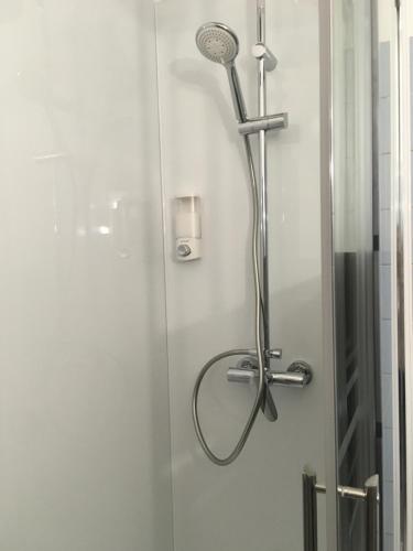 a shower with a shower head in a bathroom at L auberge du lion d or in Nanteuil-sur-Marne