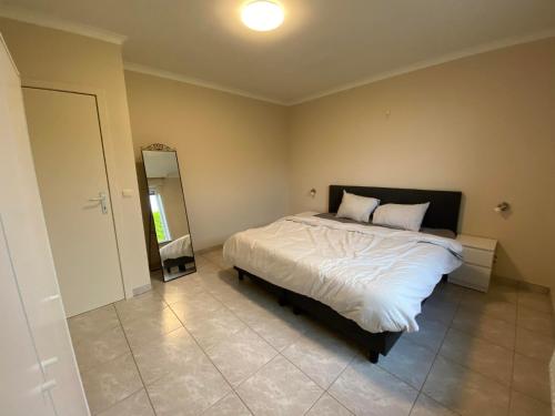 a bedroom with a large bed and a mirror at 't Cappellelandhof in Lo-Reninge