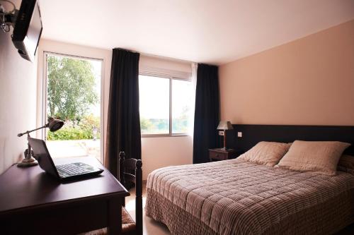 Schlafzimmer mit einem Bett und einem Schreibtisch mit einem Laptop in der Unterkunft Hotel La Longue Vue in Gennes