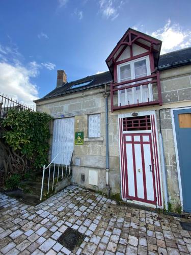 a brick house with a red door and a balcony at Chez Benjamin - Les Terrasses de Villandry in Villandry