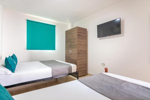 a hotel room with two beds and a flat screen tv at Hotel Casa Guajira Real in Ríohacha