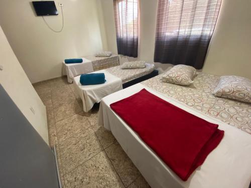 a room with three beds and a tv in it at Pousada Mãe Padroeira in Aparecida