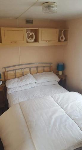 two beds in a bedroom with white sheets at 5 Berth promenade Sahara II in Ingoldmells