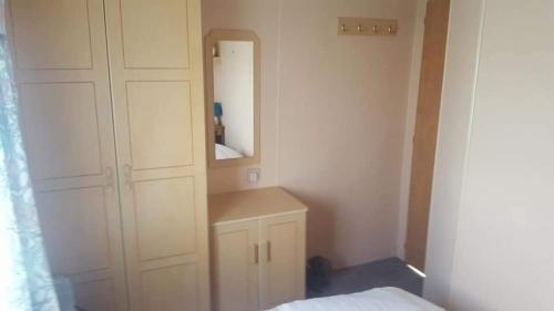 a bedroom with a white cabinet and a mirror at 5 Berth promenade Sahara II in Ingoldmells