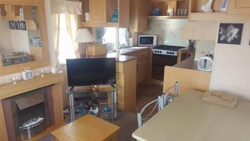 a small kitchen with a stove and a tv in it at 5 Berth promenade Sahara II in Ingoldmells