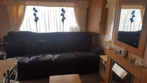 a living room with a black couch and a television at 5 Berth promenade Sahara II in Ingoldmells
