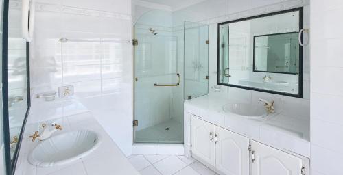 - une salle de bains blanche avec deux lavabos et une douche dans l'établissement Die Kasteel, Belvidere Estate, à Knysna
