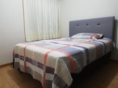 Un dormitorio con una cama con una manta. en Colibrí en Chiclayo