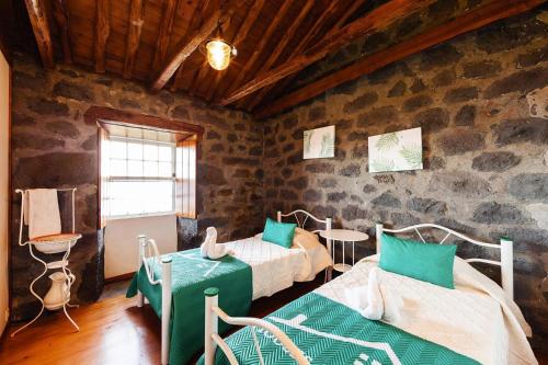 a bedroom with two beds in a room with stone walls at holiday home, Santo Amaro, Pico, Azores in Santo Amaro