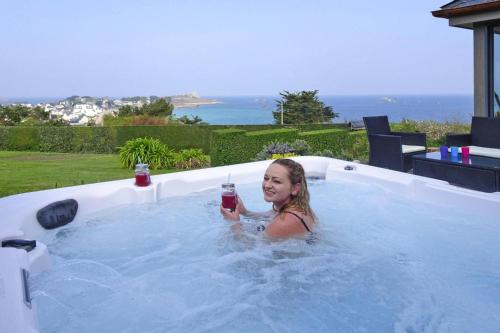 - une jeune fille prenant un verre dans un bain à remous dans l'établissement Stone House in Brittany with Sea Views, à Plougasnou