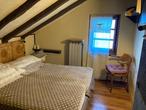 una camera con letto, finestra e sedia di Chalet Capannina a Sauze d'Oulx