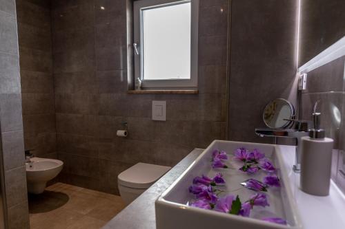 a bathroom with a sink with purple flowers in it at Villa Antea - privat heated pool, brand new villa, relaxing, rural near sea in Imotski