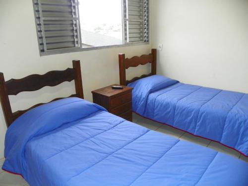 two beds in a room with blue sheets at Hotel Maia in Betim