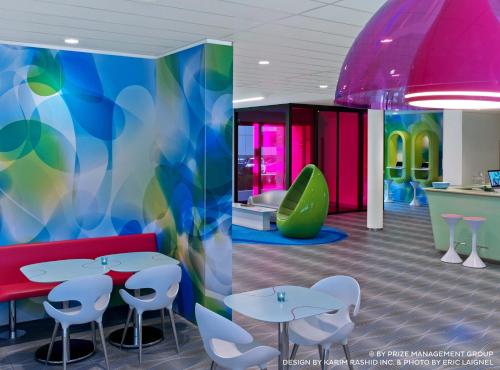 a cafeteria with tables and chairs and a colorful wall at Prize by Radisson, Hamburg City in Hamburg