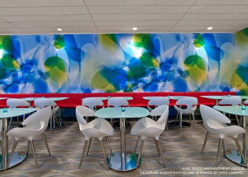 a restaurant with white chairs and a colorful wall at Prize by Radisson, Hamburg City in Hamburg