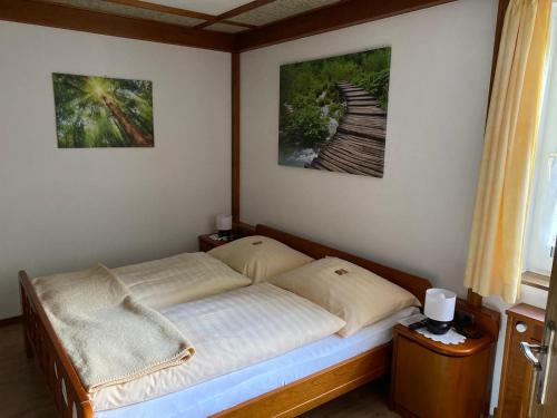 Ferienwohnung Scheiblechner في جوستلينج أن دير يبس: سرير في غرفة نوم مع صورتين على الحائط