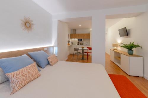 a bedroom with a large white bed with blue pillows at Apartamentos Turísticos Torres De Santiago in Úbeda