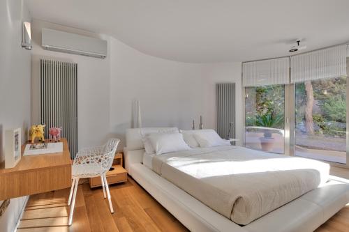 a white bedroom with a large white bed and a desk at Luxurious Villa Philoxenia in Lagonissi