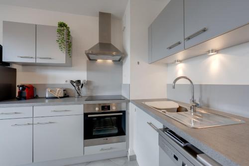 une cuisine avec des armoires blanches et un évier dans l'établissement L'Art de Ville - 2 bedroom near the city center terrace and garage, à Annecy