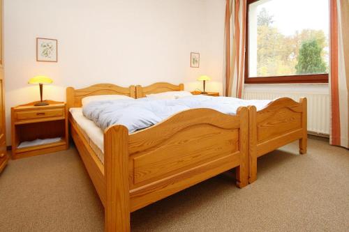 a wooden bed in a bedroom with a window at Apartment, Hahnenklee in Hahnenklee-Bockswiese