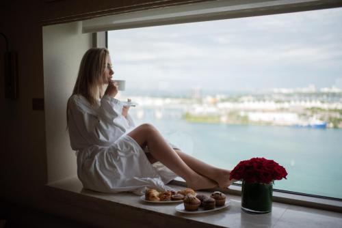 
a woman sitting on a balcony looking out at the ocean at InterContinental Miami, an IHG Hotel in Miami
