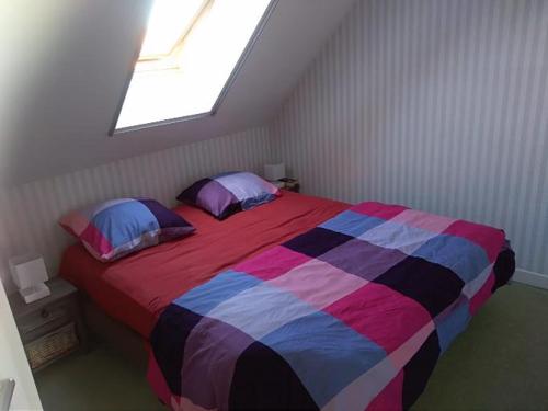 una camera da letto con un letto con una coperta e cuscini colorati di Appartement ds résidence privée avec parking privé a Berck-sur-Mer