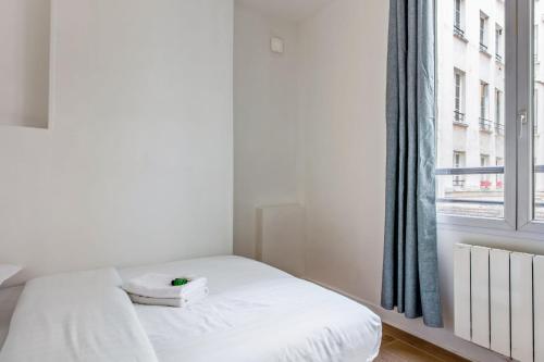 une chambre avec un lit blanc et une fenêtre dans l'établissement Appartement des Bergères - Welkeys, à Paris