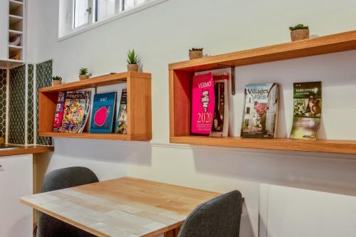 une table avec des chaises et des livres sur une étagère dans l'établissement Appartement des Bergères - Welkeys, à Paris