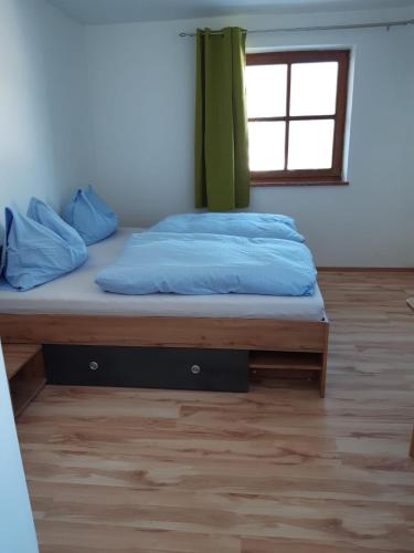 a bed with blue sheets and a window in a room at Apartment Sabrina in Sankt Johann im Pongau