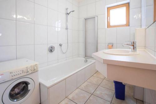 a white bathroom with a washing machine and a sink at Chalet, Hochkrimml in Krimml