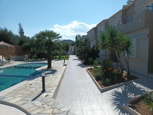 a resort yard with a swimming pool and palm trees at Secret Garden Hotel in Maleme