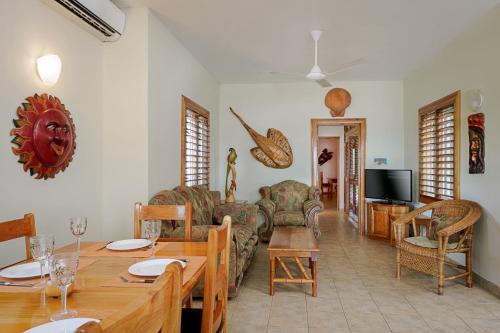 a living room with a table and chairs and a television at Beach House Condos, Negril in Negril