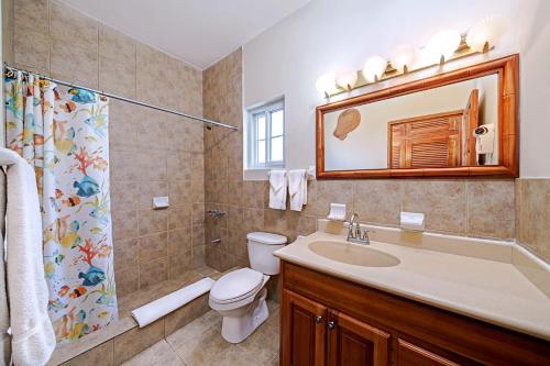 a bathroom with a sink toilet and a mirror at Beach House Condos, Negril in Negril