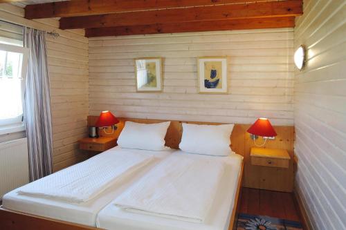 a bedroom with a white bed with two lamps at Cottage, Lissendorf in Lissendorf