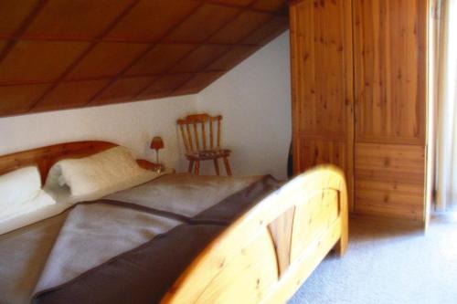 a bedroom with a large wooden bed and a chair at Vacation Home, Oberschoenau in Oberschönau