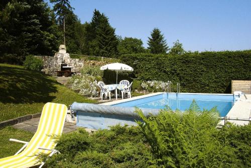 uma piscina com escorrega, uma mesa e um guarda-sol em Vacation Home, Oberschoenau em Oberschönau