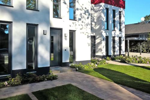 una casa blanca con puertas negras y un patio en Doppelhaushälften, Strausberg, en Strausberg