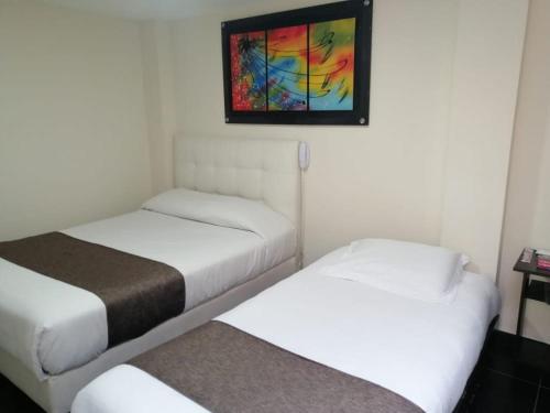 two beds in a room with a painting on the wall at Hotel Casa Galeras in Pasto